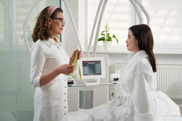 Kosmetyk pokazujący klientowi specjalny sprzęt medyczny. kosmetolog przy użyciu nowoczesnego sprzętu — Zdjęcie stockowe