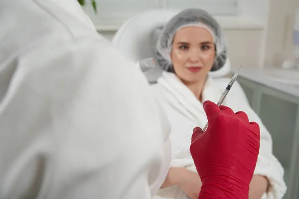 Cosmetoloog houdt spuit befor doen voor vrouw verjongende gezichtsinjecties. De expert schoonheidsspecialiste vult vrouwelijke rimpels met hyaluronzuur — Stockfoto