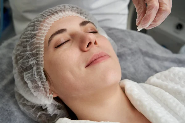 Kosmetolog czyszczący twarz pacjenta z podkładką bawełnianą w salonie piękności i spa przygotowującym do zabiegu — Zdjęcie stockowe