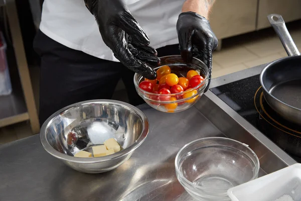 Manlig kock tillagar sallad i köket. Gourmetkocken lagar god mat i restaurangköket. Ost för stekning i skål — Stockfoto