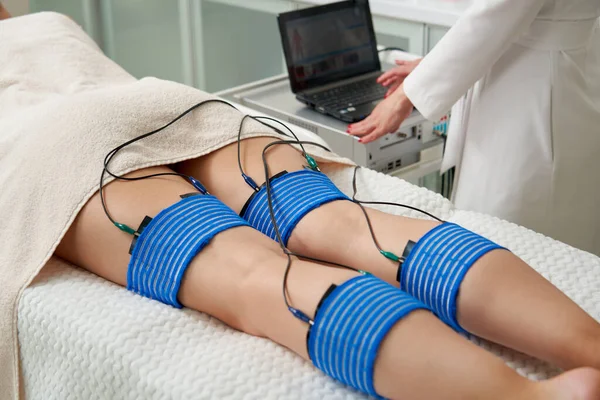 El procedimiento de mioestimulación en las piernas de una mujer en un salón de belleza. Cuidar el cuerpo con electroestimulación, reduciendo el exceso de peso — Foto de Stock