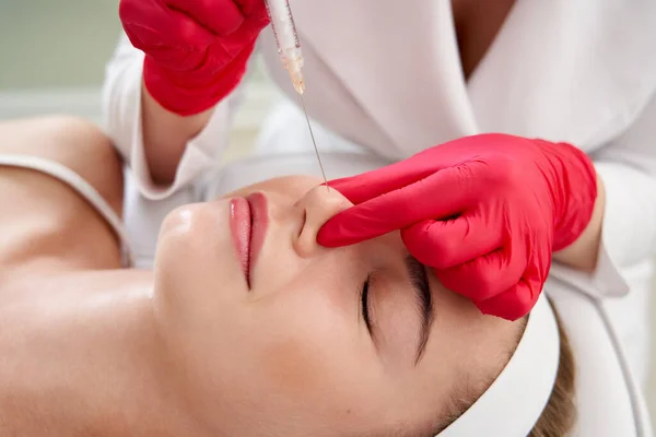 Beautician making injection in nose with syringe in beauty salon. Cosmetic rejuvenating facial treatment — Stock Photo, Image