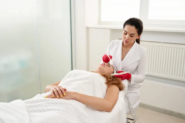 Beautiful Woman in Spa Clinic Receiving Stimulating Electric Facial Treatment From Therapist. Closeup Of Young Female Face During Microcurrent Therapy — Stock Photo, Image