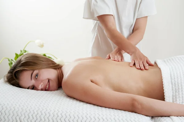 Masaż pleców. Masażysta masujący młodą kobietę na stole do masażu w salonie spa. Młoda kobieta relaksuje się podczas masażu pleców w spa. Koncepcja leczenia spa — Zdjęcie stockowe
