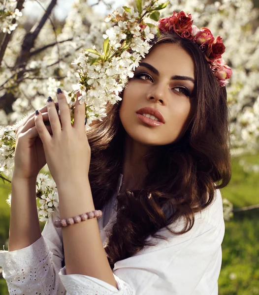 Splendida donna sensuale con i capelli scuri in abito elegante posa in giardino fiorito — Foto Stock