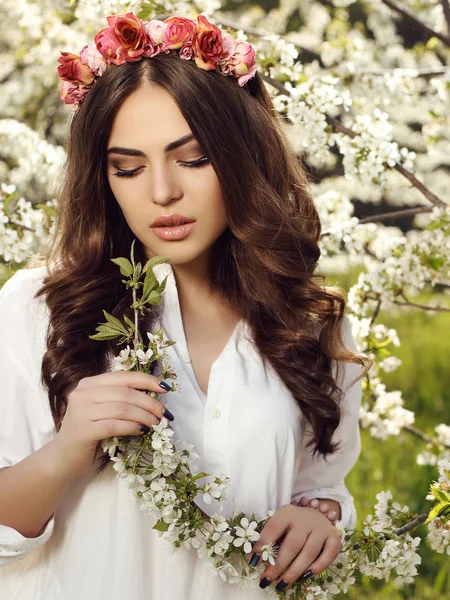 Gorgeous sensual woman with dark hair in elegant dress posing in blossom garden — Stockfoto