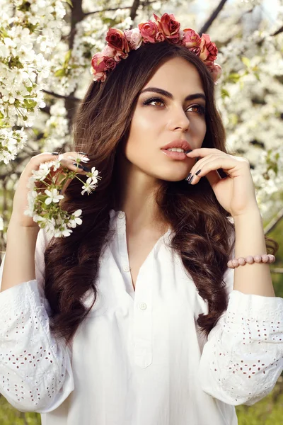 Gorgeous sensual woman with dark hair in elegant dress posing in blossom garden — Stok fotoğraf