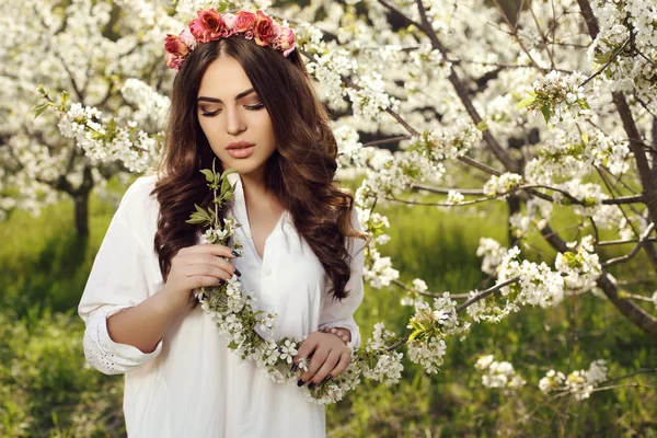 Gorgeous sensual woman with dark hair in elegant dress posing in blossom garden — Stok fotoğraf