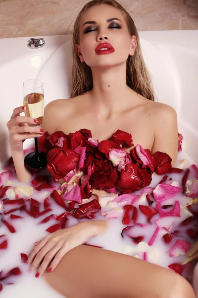 Sexy hermosa mujer con cabello rubio relajante en el baño con pétalos de rosa —  Fotos de Stock