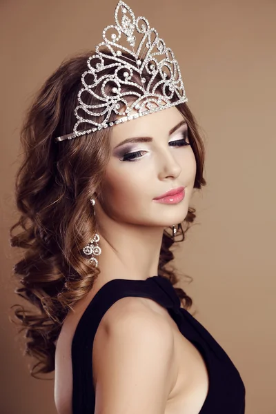 Beautiful glamour girl with dark curly hair with precious crown on head — ストック写真