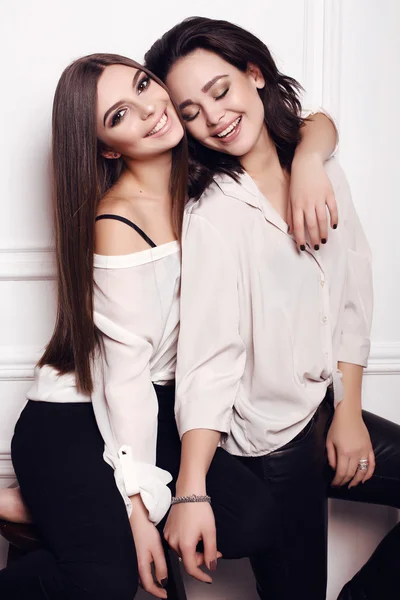 Two beautiful young women with dark hair and evening makeup, wearing elegant clothes — Stock Photo, Image