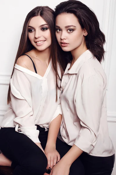 Siyah saçlı ve akşam makyaj, iki güzel genç kadın zarif giysiler giyiyor