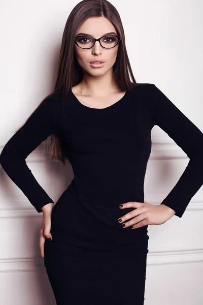 Businesslike woman with long dark hair wears elegant black dress and glasses — Stock Photo, Image