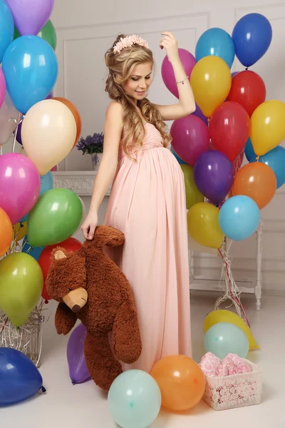 Těhotná žena má dlouhé blond vlasy v elegantní šaty, s mnoha barevnými balónů — Stock fotografie