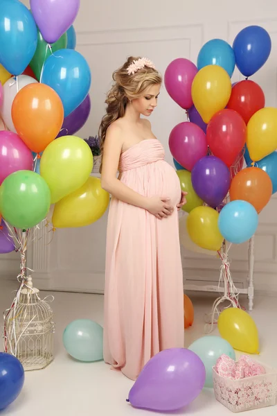 Mujer embarazada con el pelo largo y rubio en vestido elegante, con una gran cantidad de globos de aire de colores — Foto de Stock