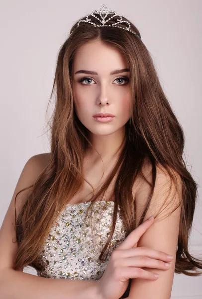 Beautiful woman with dark hair wears elegant dress and precious crown — Stock Photo, Image