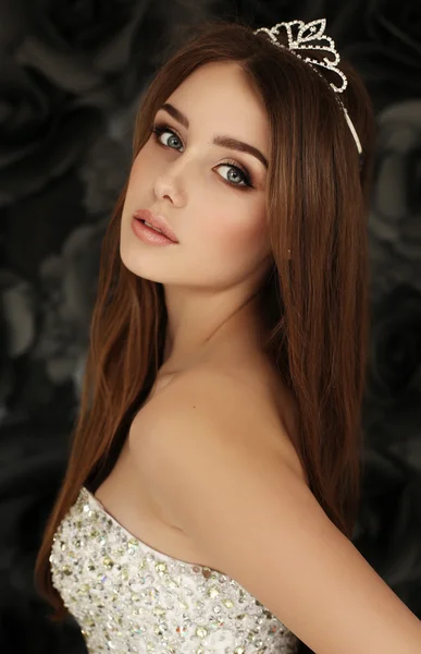 Mulher bonita com cabelo escuro usa vestido elegante e coroa preciosa — Fotografia de Stock
