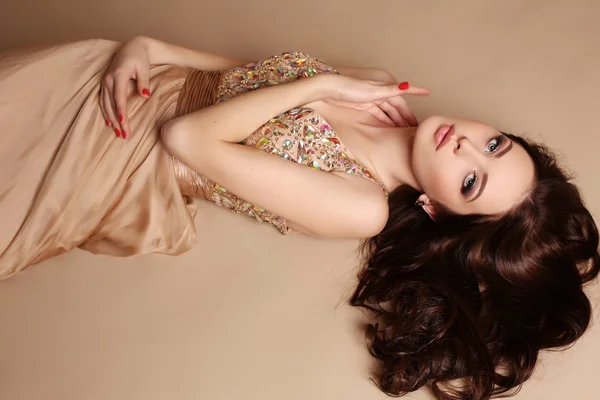 Hinreißende junge Frau mit dunklen Haaren und Abendschminke, trägt luxuriöses Kleid — Stockfoto