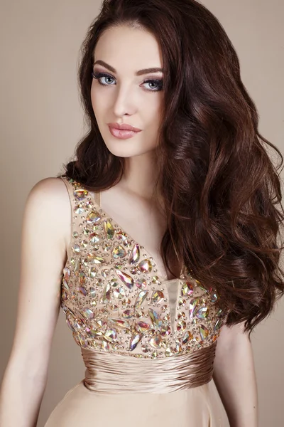 Gorgeous young woman with dark hair and evening makeup, wears luxurious dress — Stock Photo, Image