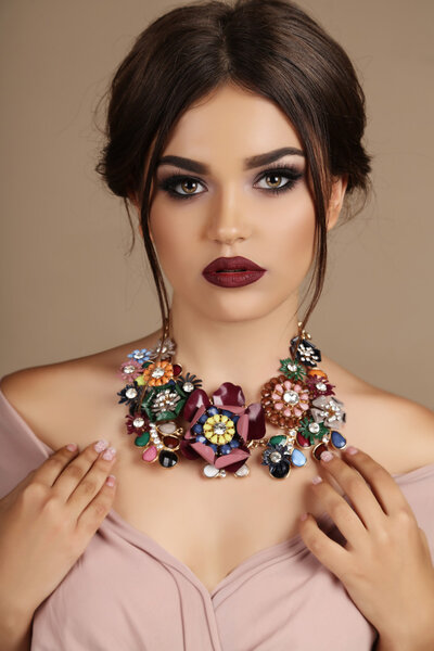 sexy woman with dark hair and bright makeup, with necklace 