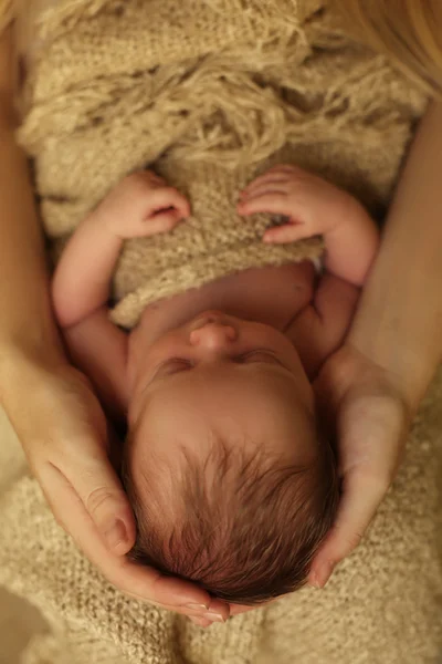 Newborn baby girl sleeping under cozy blanket in mom's hands Stock Picture