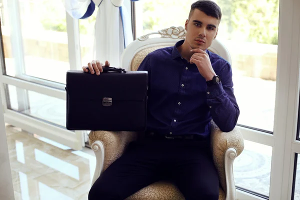Knappe man in elegante kleding met zakken poseren in interieur — Stockfoto