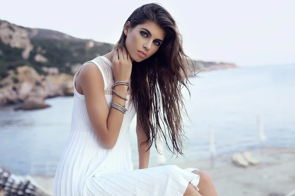 Wunderschöne Frau mit dunklen Haaren in elegantem Kleid am Strand — Stockfoto