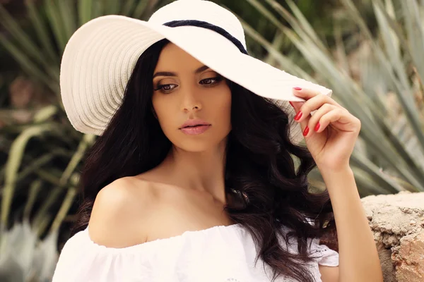 Mulher linda com cabelo escuro em elegante vestido branco e chapéu — Fotografia de Stock