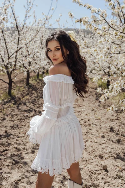 花の庭でポーズをとるエレガントなドレス姿の濃い髪の美しい女性のファッション屋外写真 — ストック写真