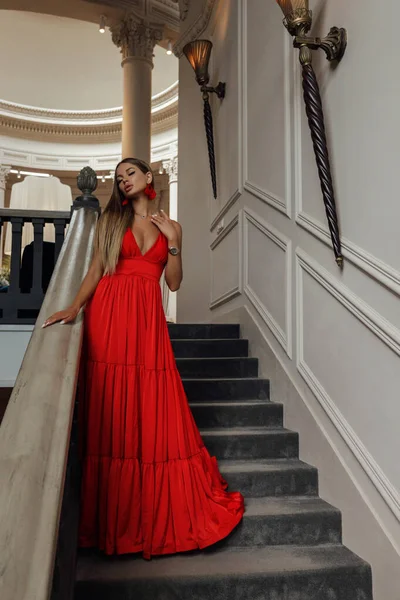 楼梯上穿着雅致的红色礼服 金发美女的时尚内景 — 图库照片