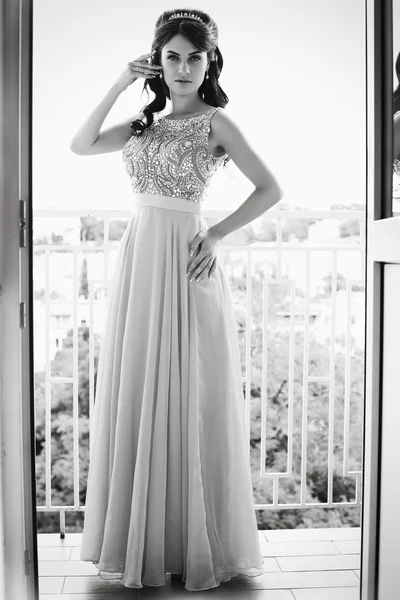 Красивая женщина в роскошном платье позирует на балконе — стоковое фото