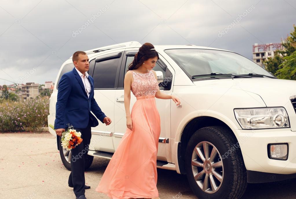 wedding photo of beautiful couple beside a car