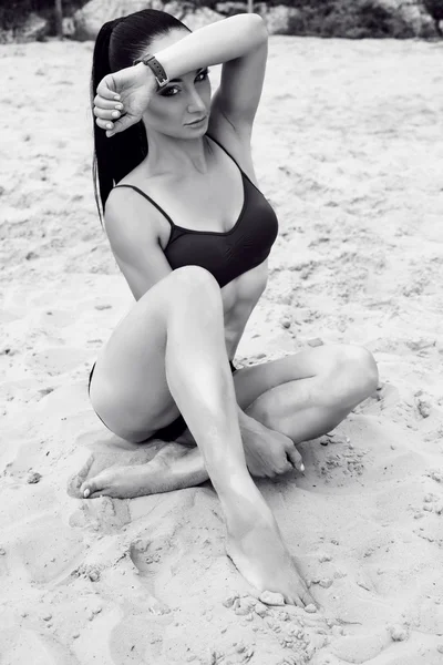 Mooie vrouw met donker haar in sportieve kleding die zich voordeed op strand — Stockfoto