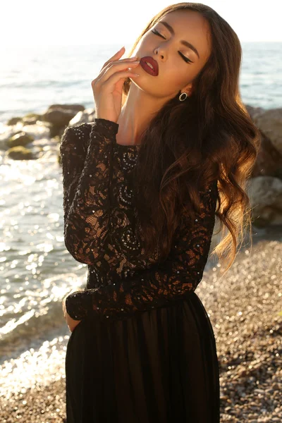 Beautiful model in lace black dress posing on beach — Stock Photo, Image