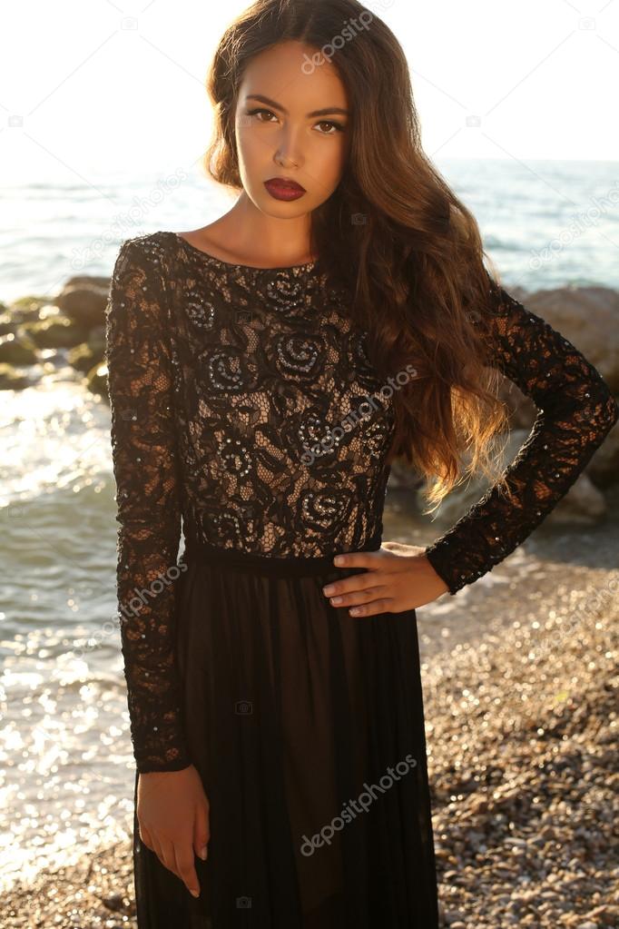 beautiful brunette in black lace dress posing on beach