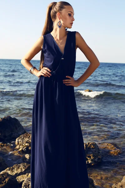 Hübsche Brünette mit langen Haaren in elegantem Kleid posiert am Strand — Stockfoto
