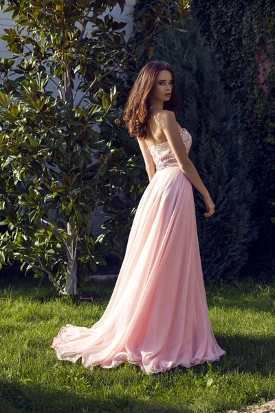 Hübsche Brünette in luxuriösem Kleid posiert im Park — Stockfoto