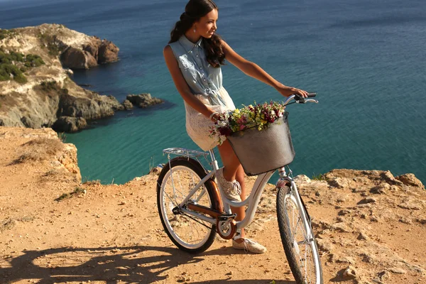 Pretty girl riding a bicycle along the sea coast — Stock Photo, Image