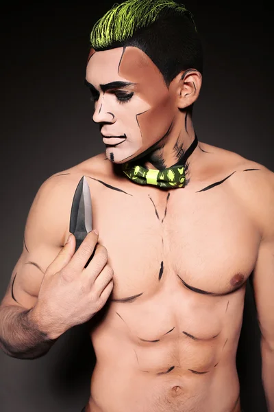 Muscular man with painted face and chest with dagger — Stock Photo, Image