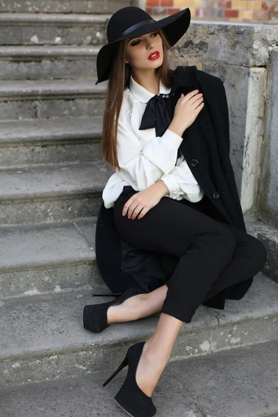 Beautiful ladylike woman in elegant clothes sitting on stairs in park — Stock Photo, Image