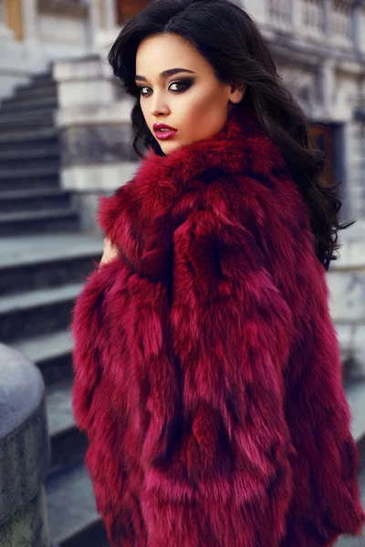 Όμορφη κοπέλα με σκούρα μαλλιά, φορώντας κόκκινο γούνινο παλτό μόδας — Φωτογραφία Αρχείου
