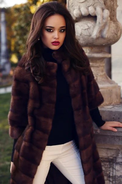 Beautiful girl with dark hair wearing fashion red fur coat Stock