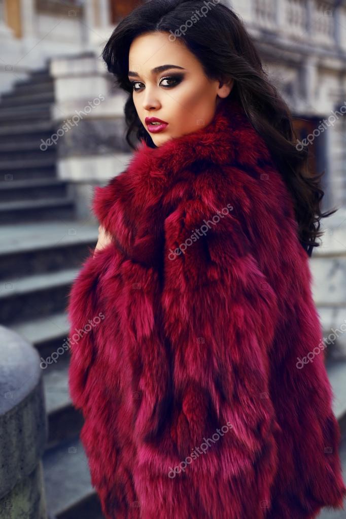 Beautiful girl with dark hair wearing fashion red fur coat Stock