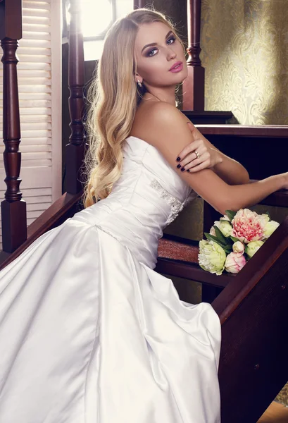 Belle mariée aux cheveux blonds dans une élégante robe de mariée avec bouquet — Photo