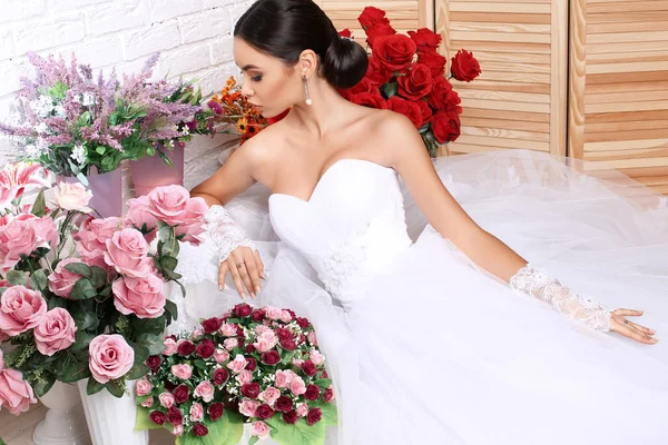 꽃 들 사이에서 포즈를 취하는 우아한 웨딩 드레스에 아름 다운 신부 — 스톡 사진