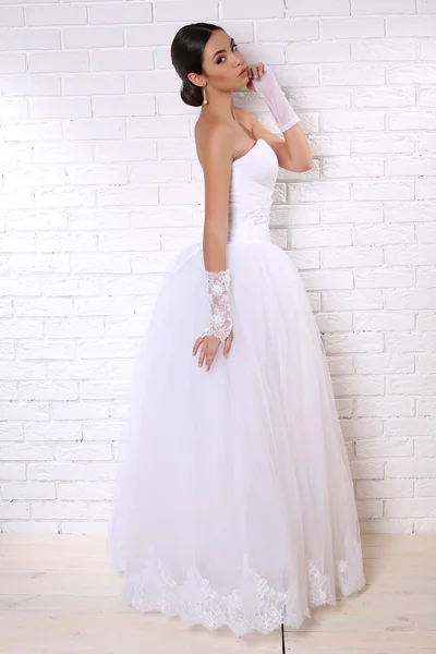 Mooie bruid met donker haar in elegante trouwjurk met accessoires — Stockfoto