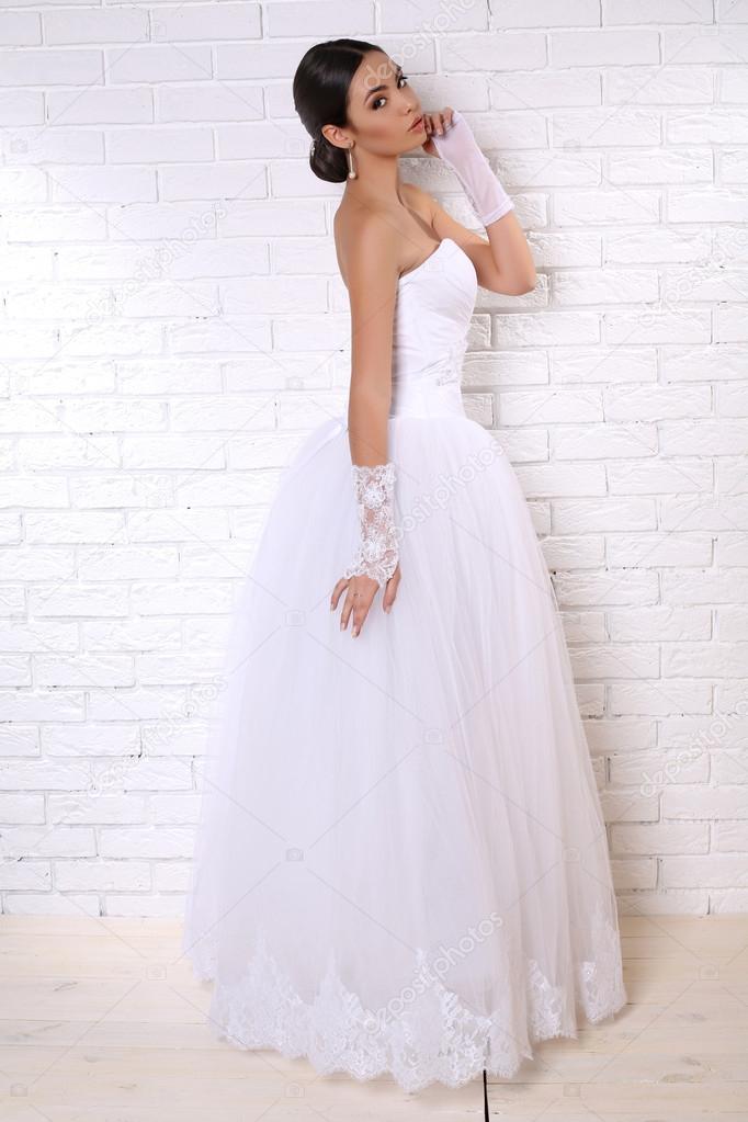 beautiful bride with dark hair in elegant wedding dress with accessories