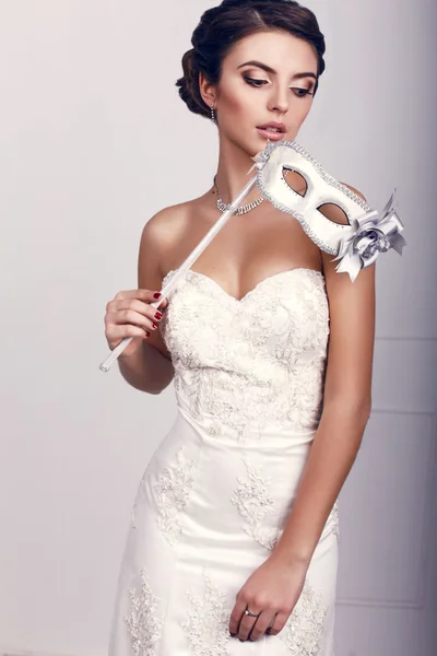 Beautiful girl with dark hair wearing elegant dress,holding a mask in hand — Stock Photo, Image