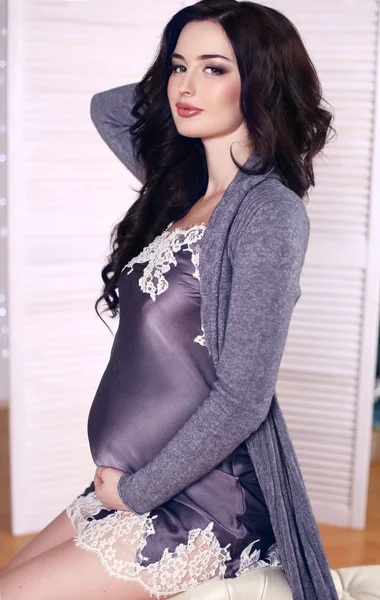 Krásná těhotná žena s tmavými vlasy, pózuje v hedvábných šatech — Stock fotografie