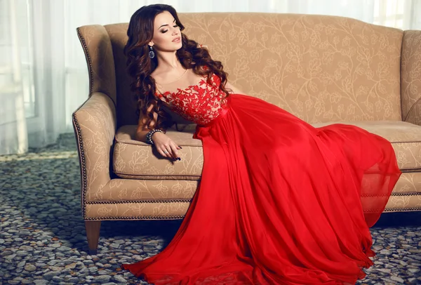 Vacker kvinna med långt mörkt hår bär lyxiga röd klänning — Stockfoto
